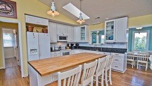 Una cocina con armarios blancos, una isla de madera y taburetes de bar.