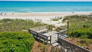Un paseo marítimo de madera que conduce a una playa con vista despejada al océano.