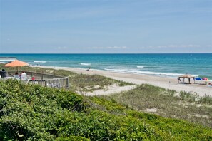 A beach view with a wooden deck and umbrellas.