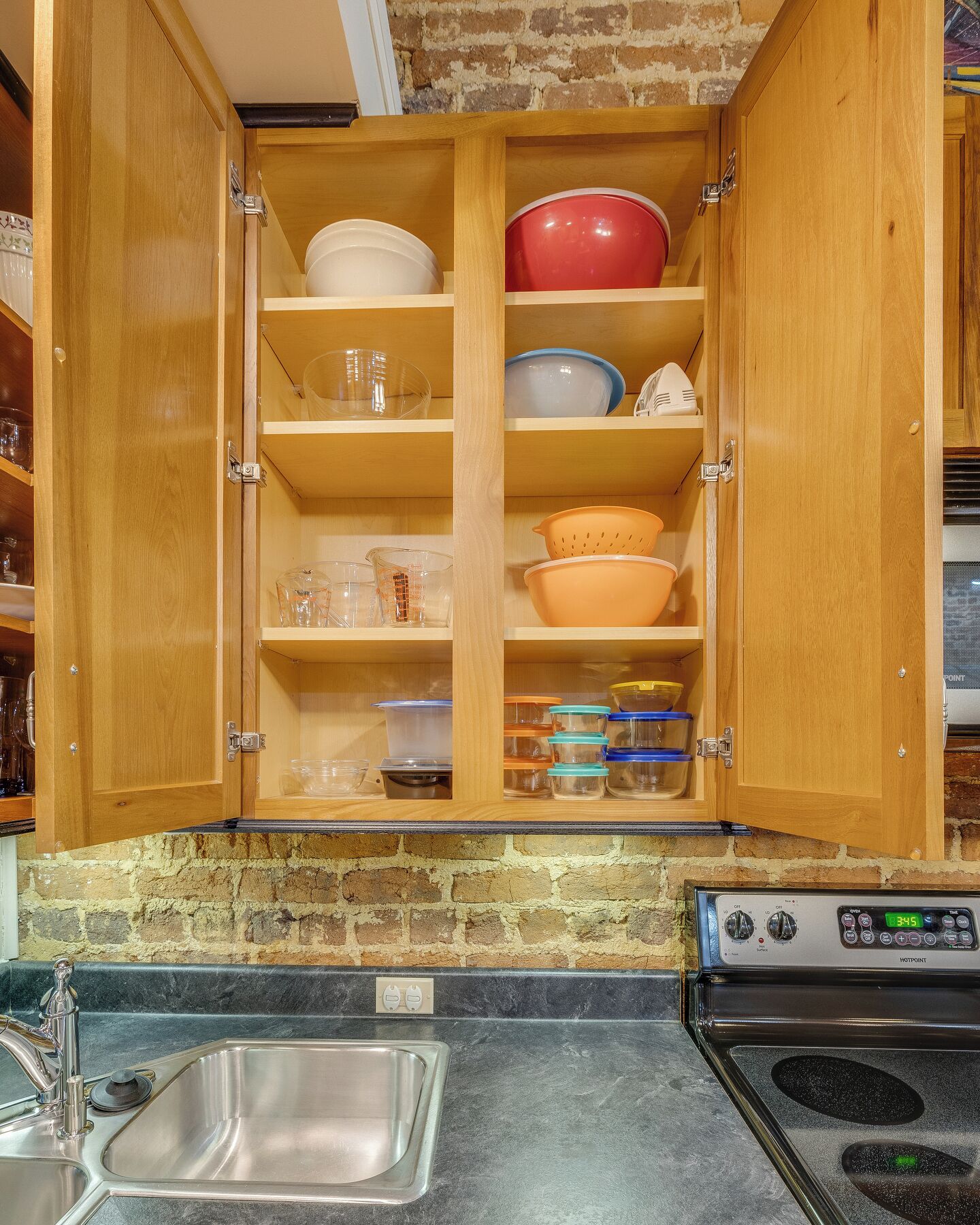 A kitchen with wooden cabinets, a stainless steel sink, and a built-in oven.