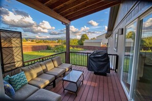 Una terraza techada con un sofá, una mesa y una parrilla.
