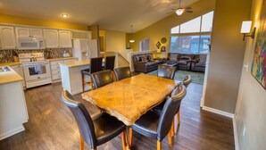 A spacious kitchen with white cabinets, a dining table with chairs, and a living area with a sofa and a TV. - Beautiful Spokane Valley Home (Spokane Valley)