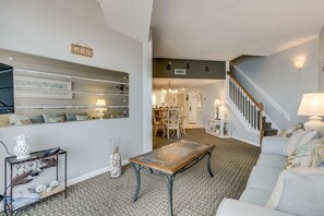 A living room with a sofa, coffee table, and a staircase leading to another room.