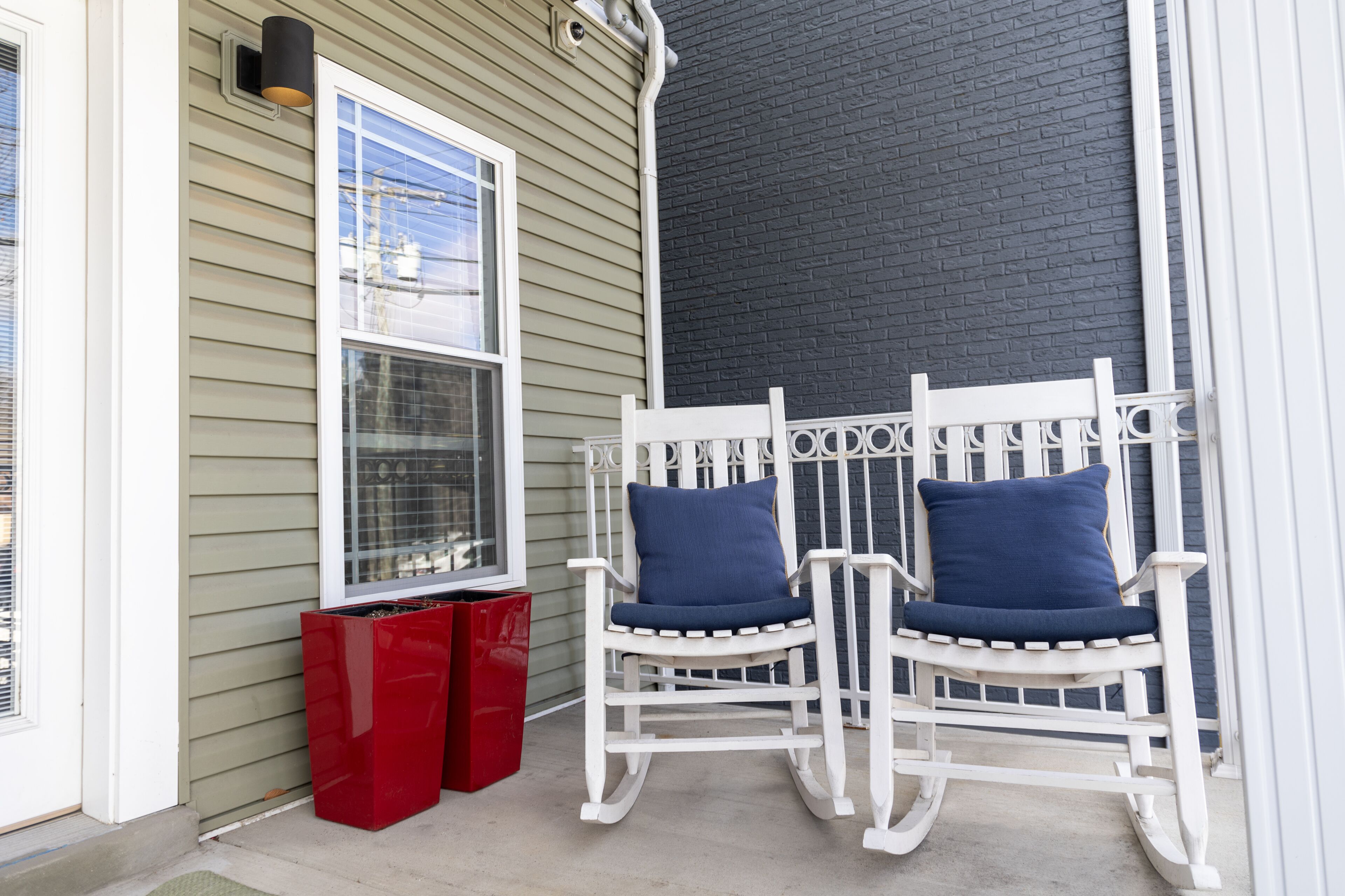 A porch with two rocking chairs and a red trash bin.