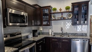 Una cocina moderna con armarios de madera oscura, electrodomésticos de acero inoxidable, encimeras de granito y lavavajillas integrado.