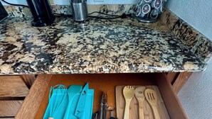 A kitchen drawer with utensils, a cutting board, and a knife. - SURFERS DREAM STUDIO (Waianae)