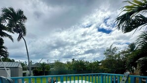A turquoise deck with two rocking chairs and a small table, surrounded by a blue railing. - SURFERS DREAM STUDIO (Waianae)