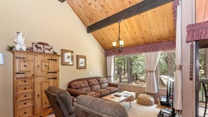A cozy living room with a wooden ceiling, a sofa, a coffee table, and a fireplace. - Walk to Snow Summit! National Forest & Ski Slope Views! Close to Hiking Trails! (Big Bear Lake)
