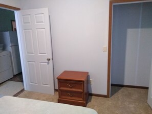 A bedroom with a bed, a dresser, and a door leading to another room.