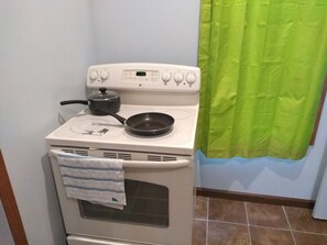 A kitchen with a stove, a frying pan, and a pot.