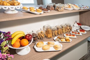 Una mesa de buffet con diversos alimentos, incluyendo pasteles, sándwiches y frutas.