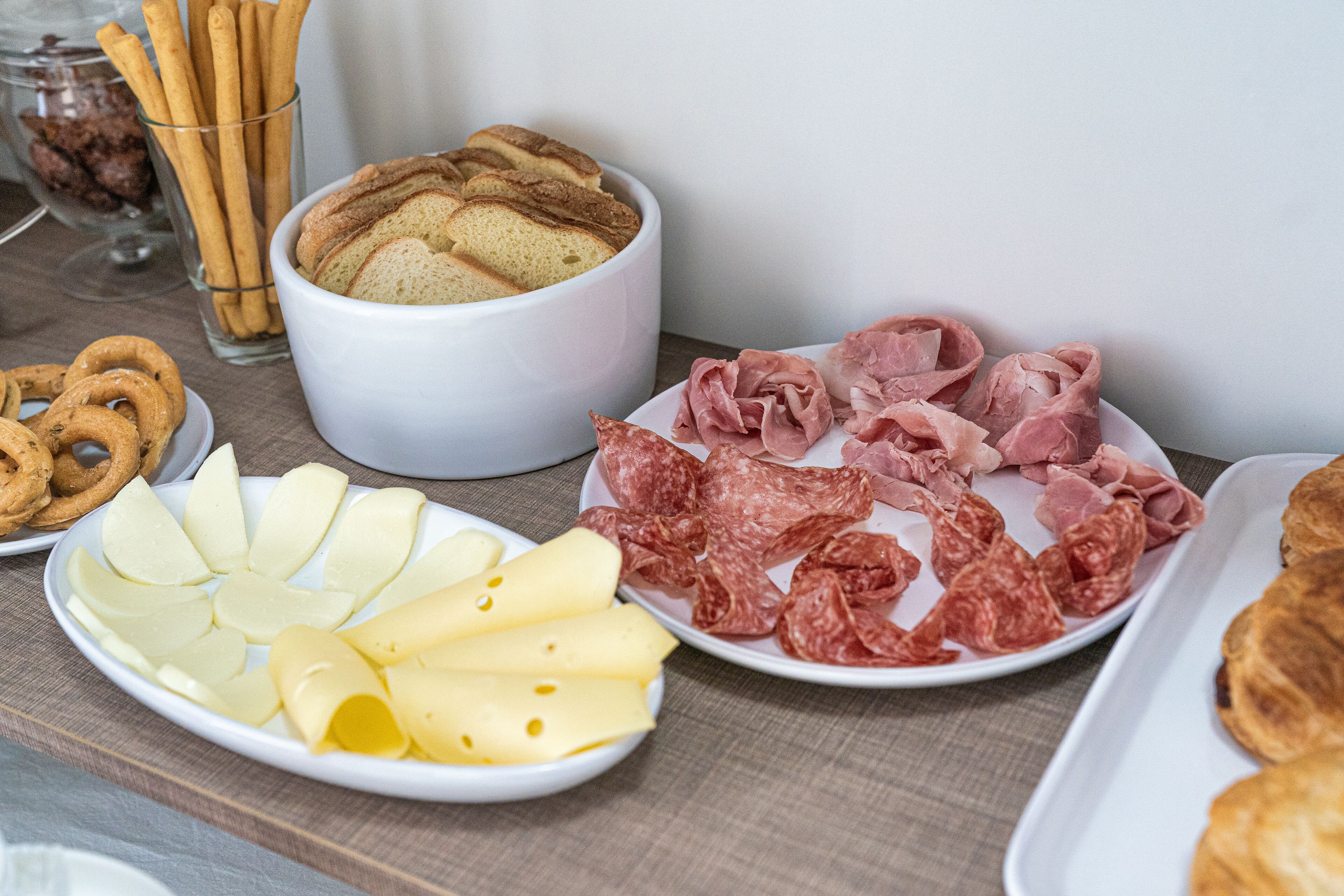 Una mesa con diversos alimentos, como pan, queso y embutidos.
