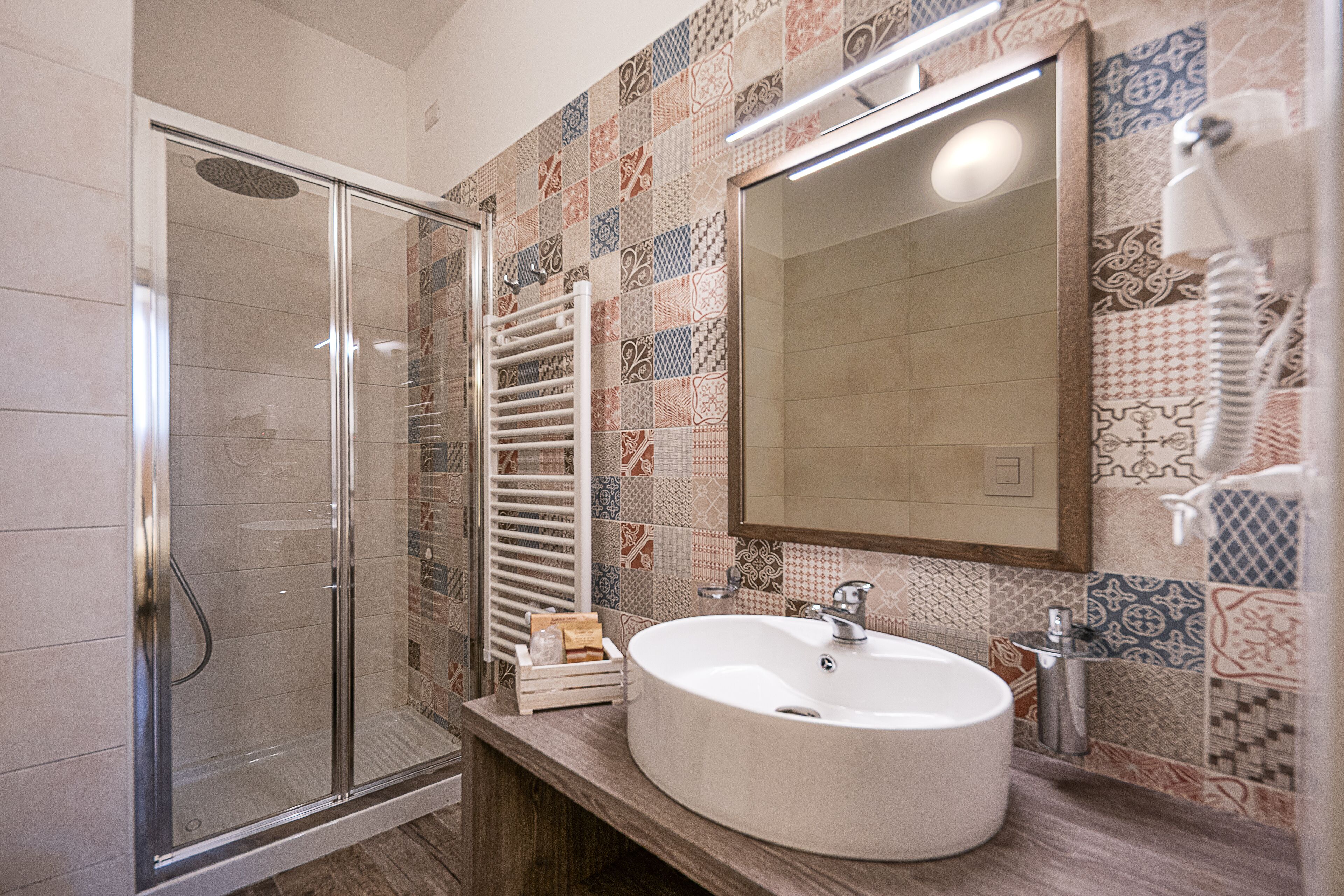 A bathroom with a glass shower enclosure, a white sink, and a tiled backsplash.
