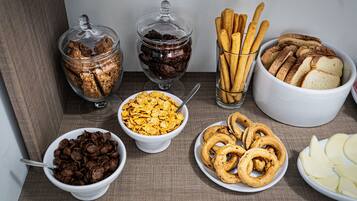 A table with various food items including cookies, cereal, pretzels, and sliced bread.