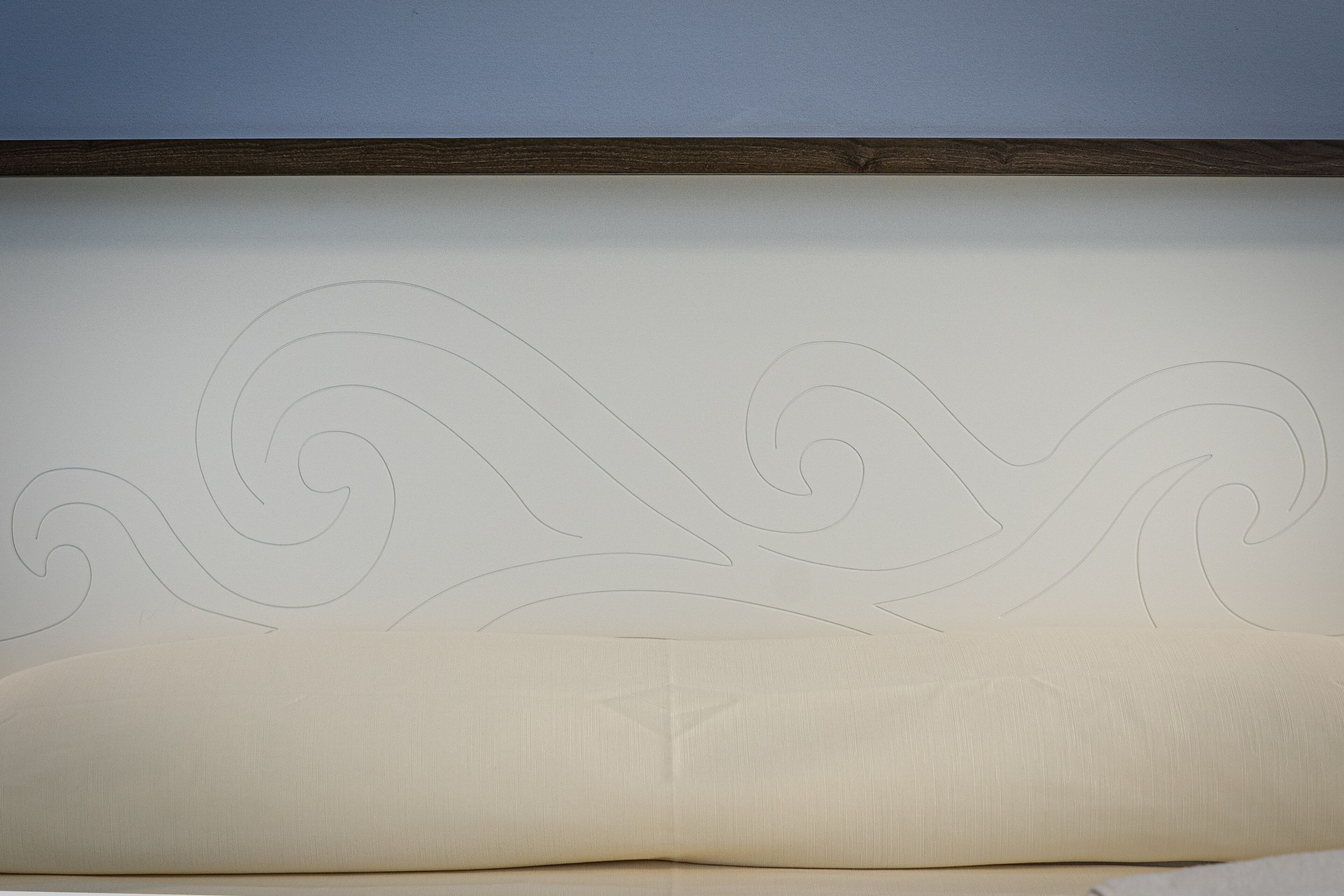 Una cama con cabecera que presenta un diseño sencillo y elegante de olas.