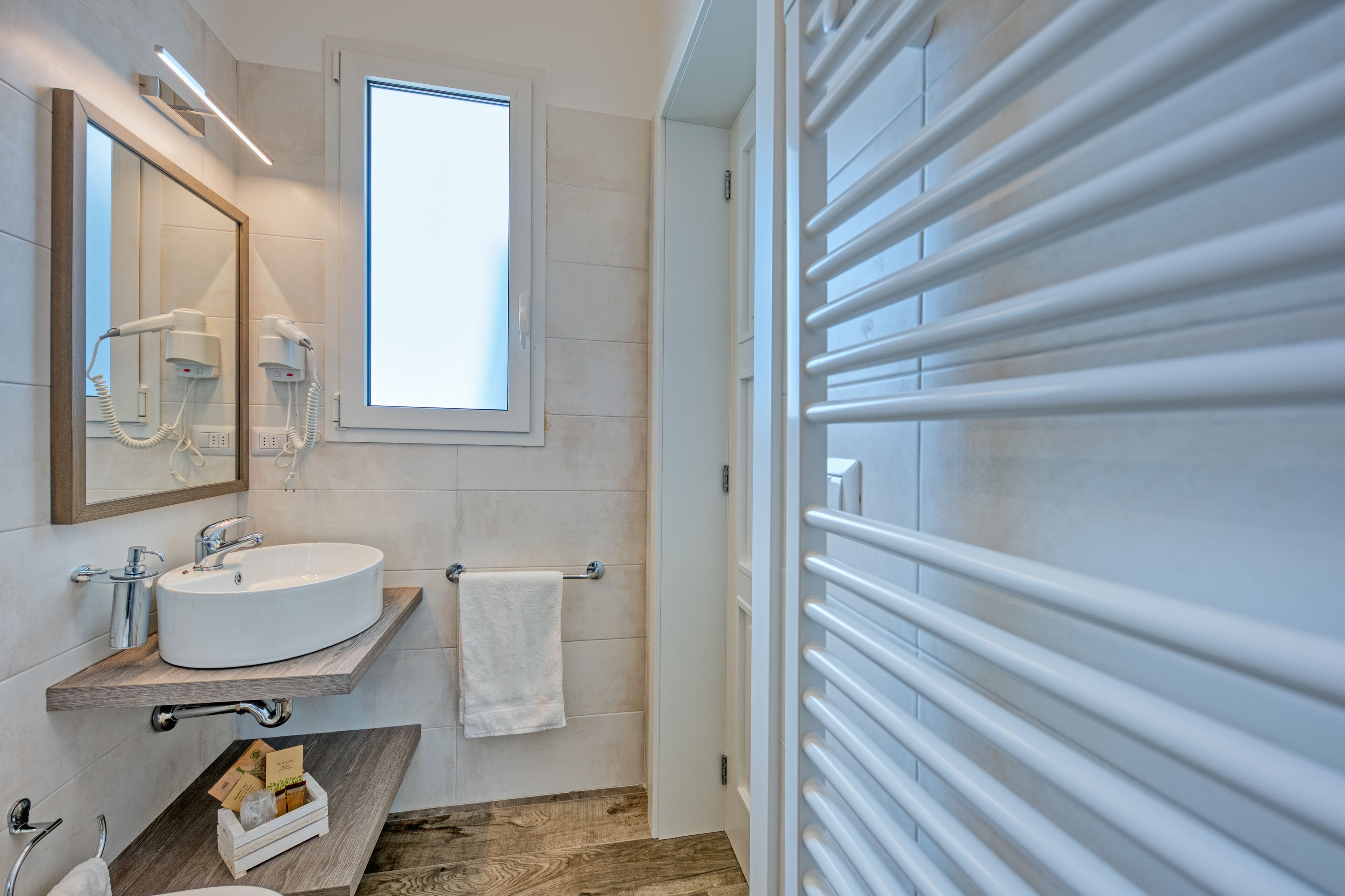 Une salle de bain moderne avec un lavabo blanc, un miroir, un sèche-cheveux et un porte-serviettes.