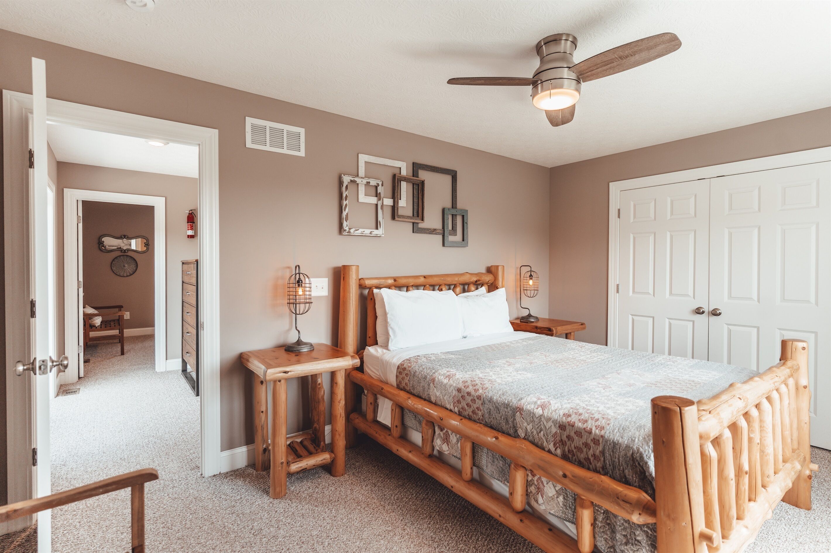 A bedroom with a wooden bed, bedside tables, a ceiling fan, and a door leading to another room.