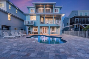 A two-story house with a swimming pool, outdoor seating, and a fenced patio area.
