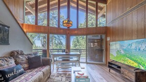 A spacious living room with a large TV, wooden furniture, and a view of the outdoors. - Cub's cabin Family house inside the gates of Yosemite Park!!! (Yosemite National Park)