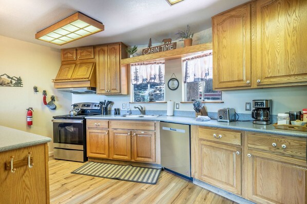 Una cocina con armarios de madera, electrodomésticos de acero inoxidable y una ventana con vistas a un bosque.