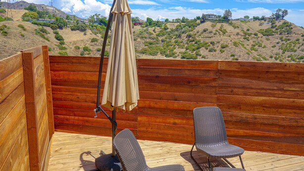 A wooden deck with two wicker chairs and a beige umbrella. - Tiny Home -  Hollywood Sign View (Los Angeles)