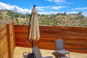 A wooden deck with two wicker chairs and a beige umbrella. - Tiny Home -  Hollywood Sign View (Los Angeles)
