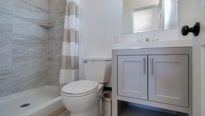 A bathroom with a bathtub, toilet, and a cabinet. - Tiny Home -  Hollywood Sign View (Los Angeles)