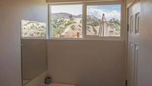 A bathroom with a large window offering a view of a desert landscape. - Tiny Home -  Hollywood Sign View (Los Angeles)