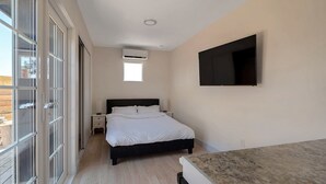 A bedroom with a bed, a TV mounted on the wall, and a window with a view of the outdoors. - Tiny Home -  Hollywood Sign View (Los Angeles)