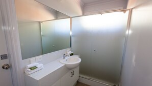 A modern bathroom with a white sink, mirror, and frosted glass shower enclosure. - 2 Bedroom Chalet offers 2 separate bedrooms with a large living/dining area and balcony. (Margaret River)