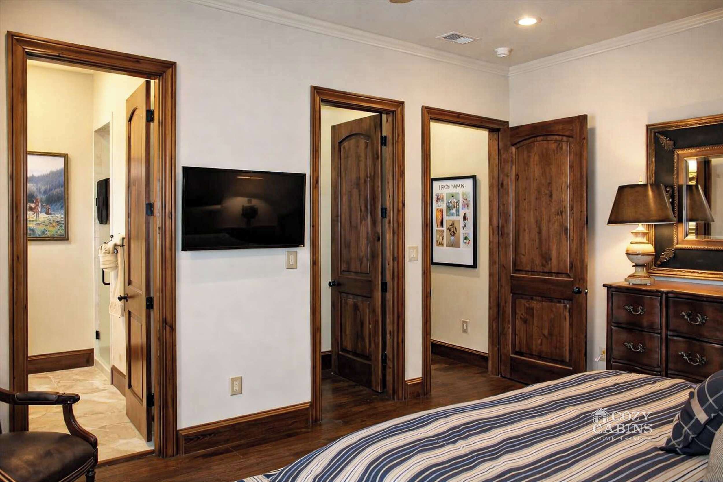 Un dormitorio con cama, puertas de madera, televisor y cómoda.