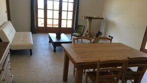 Een woonkamer met een houten eettafel, twee stoelen, een bank en een salontafel.