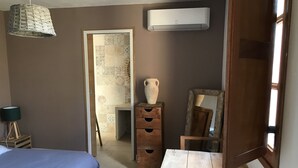 Een slaapkamer met een bed, een dressoir, een spiegel en een airconditioning.