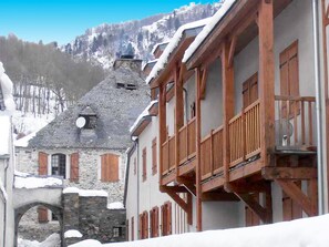 A traditional stone building with wooden balconies and a snow-covered mountain backdrop. - 3 Rooms with Terrace, 50m² for 8 People (Vignec)