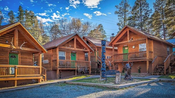 Une rangée de cabanes en bois, avec une pancarte d’accueil, une véranda couverte et un escalier menant à l’étage supérieur.