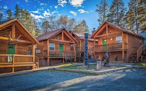 Une rangée de cabanes en bois, avec une pancarte d’accueil, une véranda couverte et un escalier menant à l’étage supérieur.