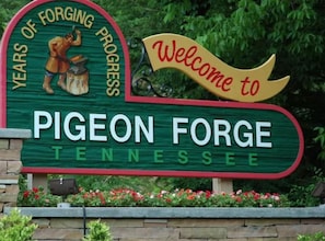 Un panneau d’accueil pour Pigeon Forge, dans le Tennessee, représentant un forgeron et arborant un motif rouge et vert.