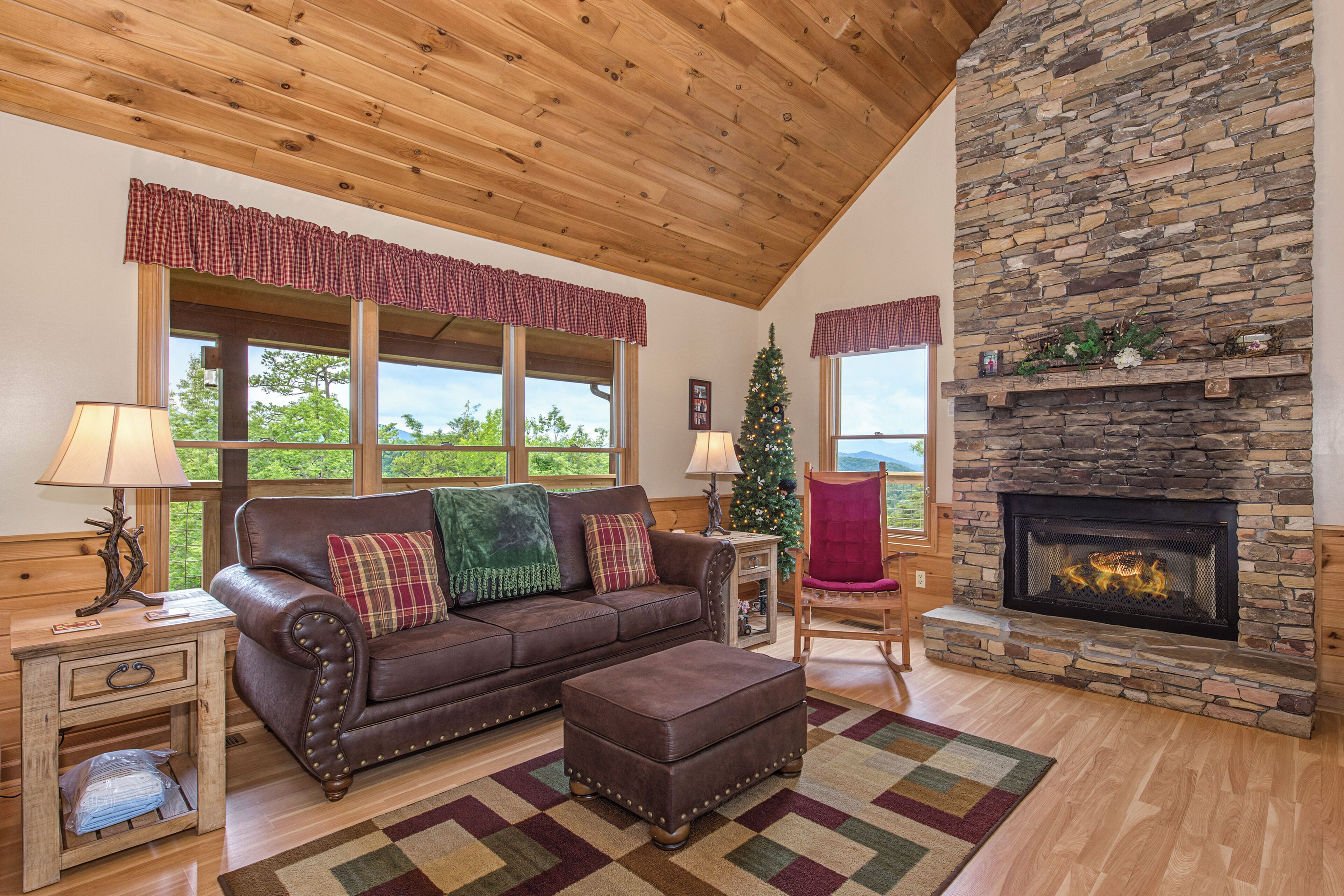 A cozy living room with a stone fireplace, leather sofa, and a view of the outdoors.