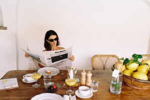 A dining table with a newspaper, a bowl of lemons, and various breakfast items. - Villa Arnica (Lana)