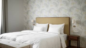 A neatly made bed with white linens, a wooden headboard, and a bedside table with a lamp.