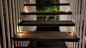 A wooden staircase with multiple steps, surrounded by vertical metal panels. - The Hide Hostel at Canggu - Adults Only (Canggu)