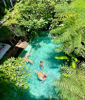 An outdoor swimming pool surrounded by lush greenery.