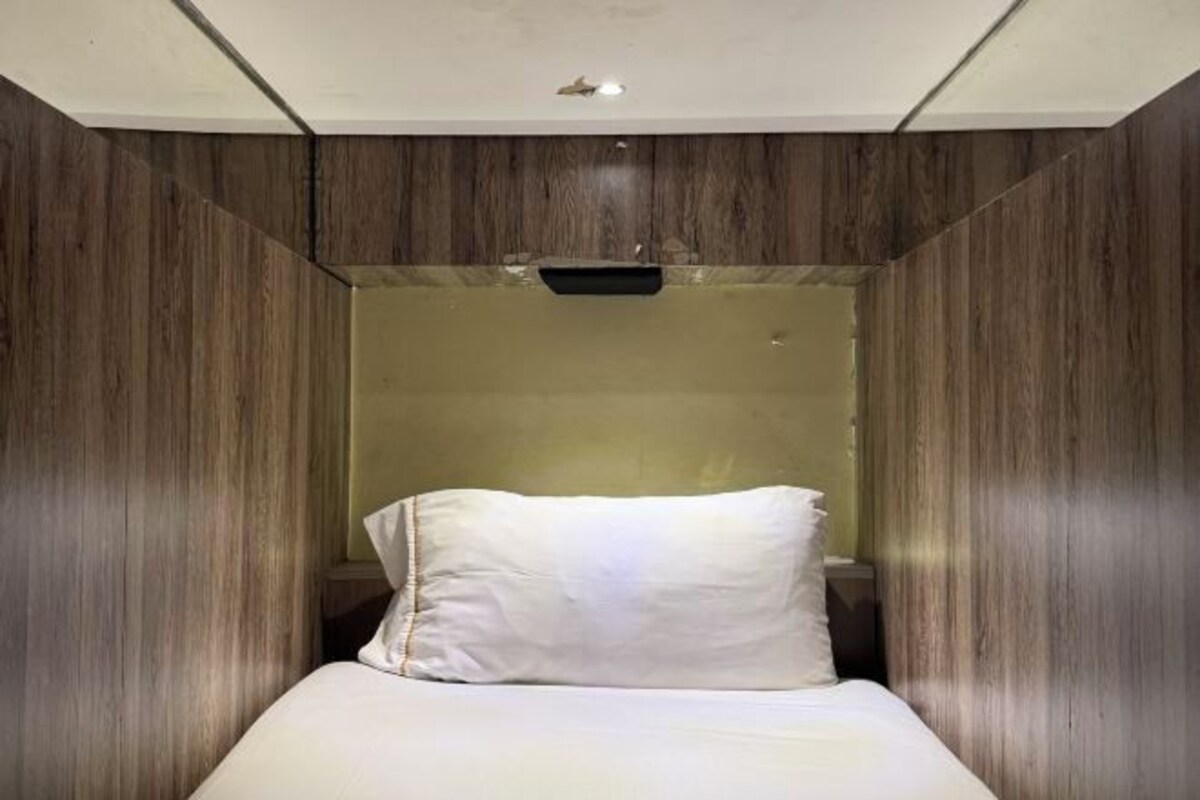 A modern room with a bed, a small bedside table, and a wall-mounted shelf.