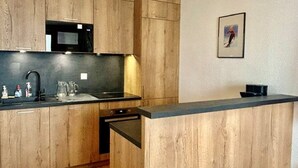 A kitchen with wooden cabinets, a microwave, a sink, and a small countertop. - 4-Room Rental with Balconies for 8 in Puy-Saint-Vincent (Puy-Saint-Vincent)