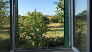 A window with green shutters, a view of a tree, and a grassy field. - GITE DE CHARME 3 Etoiles, Label Clef Verte, Wifi Fibre, Futuroscope 86800 LAVOUX (Lavoux)