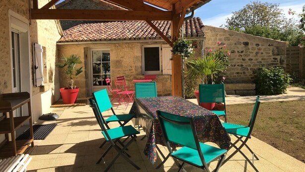 An outdoor patio with a wooden pergola, a tiled table, and green chairs. - GITE DE CHARME 3 Etoiles, Label Clef Verte, Wifi Fibre, Futuroscope 86800 LAVOUX (Lavoux)