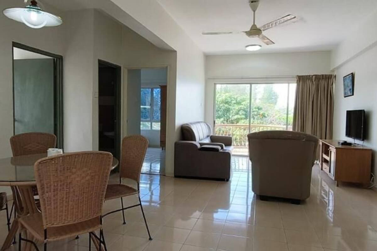 A spacious living area with a dining table, wicker chairs, a sofa, and a television.