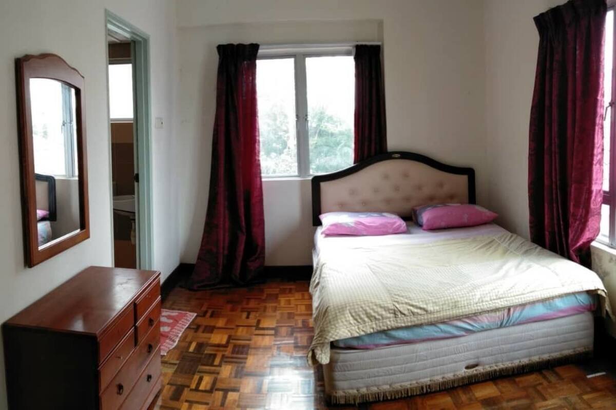 A bedroom with a bed, a dresser, a window with curtains, and a mirror on the wall.