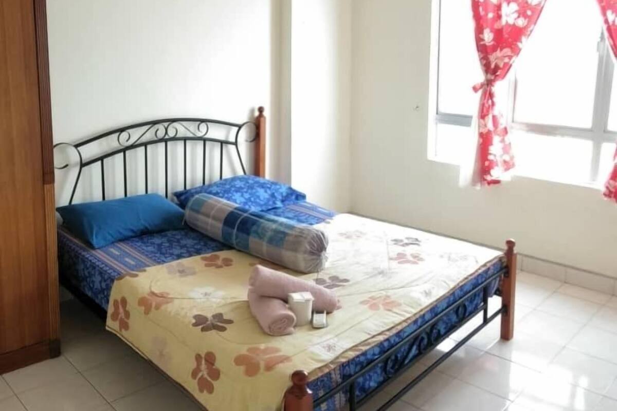 A bedroom with a bed, pillows, a blanket, and a wooden headboard.