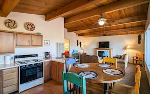 A cozy kitchen with wooden cabinets, a stove, and a dining area with a round table and chairs.